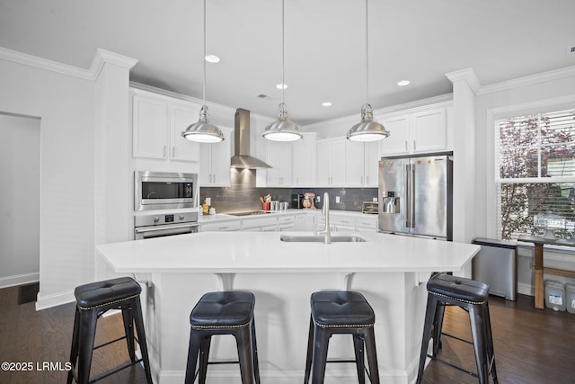 kitchen with wall chimney exhaust hood, crown molding, appliances with stainless steel finishes, and a sink