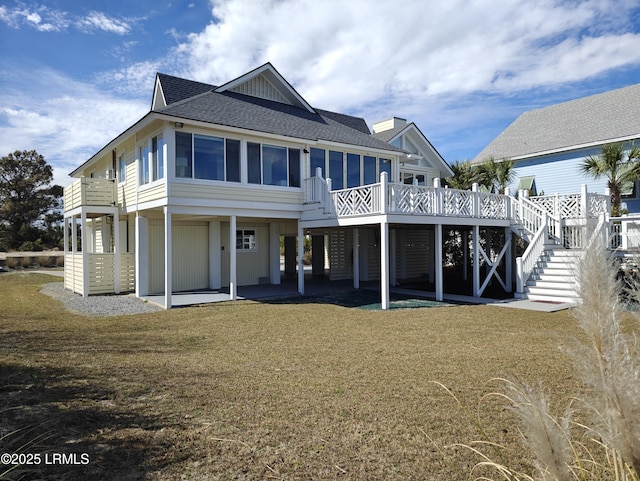 back of property featuring a shingled roof, a sunroom, a yard, stairway, and a patio area