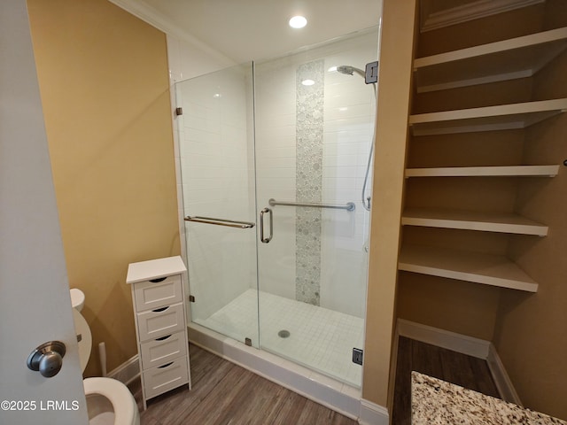 full bathroom with toilet, wood finished floors, baseboards, a closet, and a shower stall