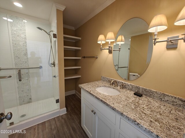 bathroom with a stall shower, baseboards, wood finished floors, crown molding, and vanity