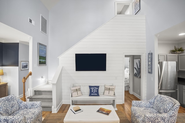 living area with stairs, dark wood-type flooring, a towering ceiling, and visible vents