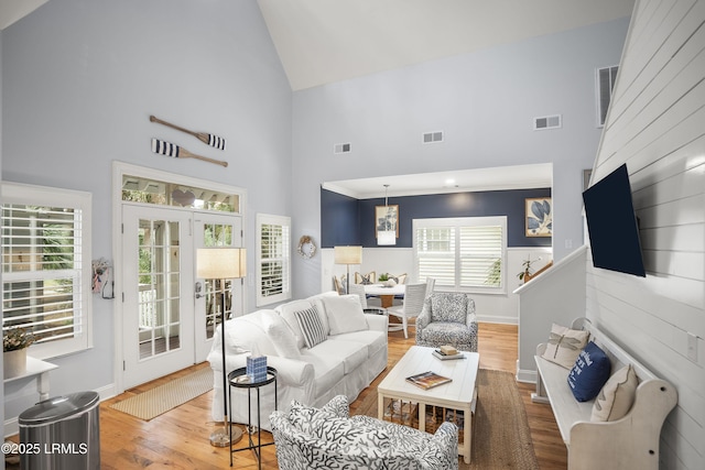 living area with visible vents, wood finished floors, french doors, and high vaulted ceiling