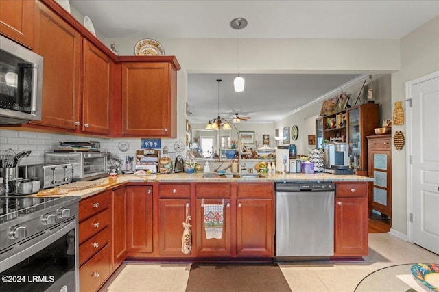 kitchen featuring light tile patterned floors, appliances with stainless steel finishes, hanging light fixtures, decorative backsplash, and kitchen peninsula