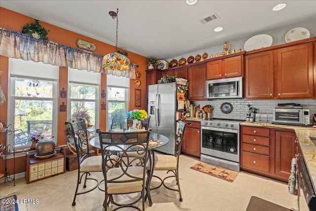 kitchen with pendant lighting, appliances with stainless steel finishes, and backsplash