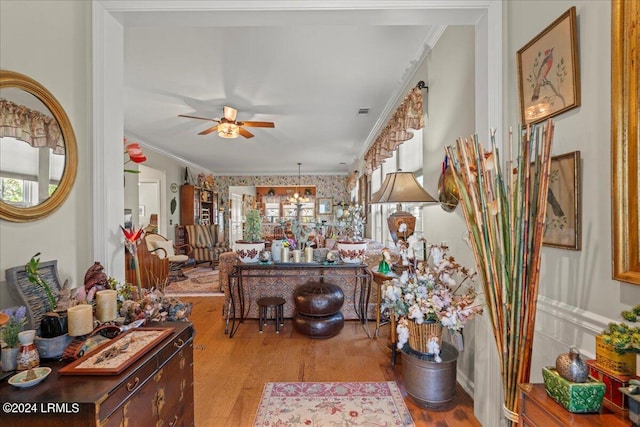 living room with ornamental molding, ceiling fan with notable chandelier, and light wood-type flooring