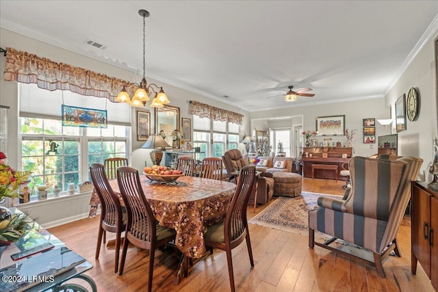 dining room featuring crown molding, light hardwood / wood-style flooring, a healthy amount of sunlight, and ceiling fan with notable chandelier