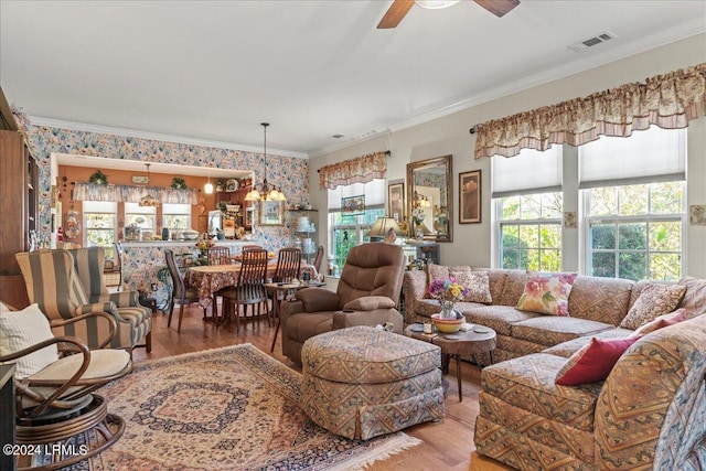 living room with ornamental molding, ceiling fan with notable chandelier, and hardwood / wood-style floors