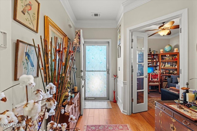 doorway with ornamental molding, french doors, and light wood-type flooring