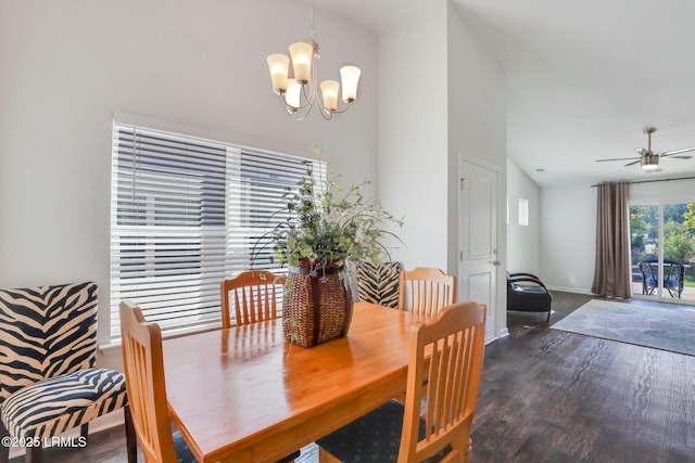 dining space featuring vaulted ceiling, ceiling fan with notable chandelier, dark wood finished floors, and baseboards