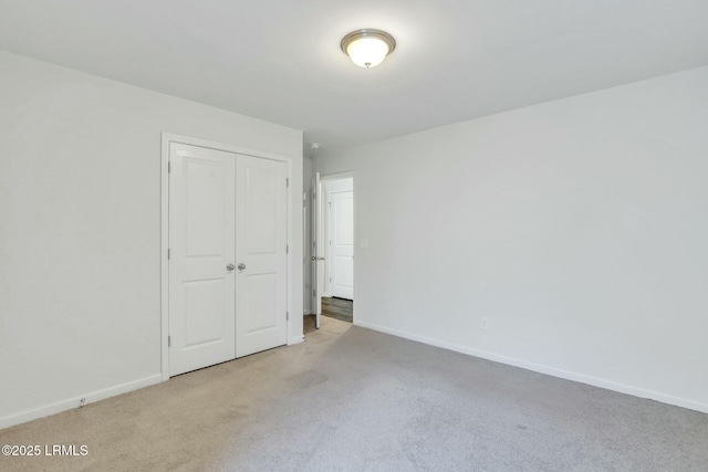 unfurnished bedroom featuring a closet, light carpet, and baseboards