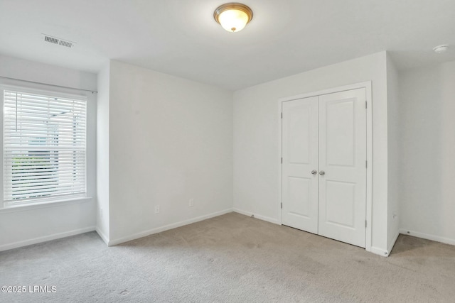 unfurnished bedroom featuring a closet, visible vents, and light carpet