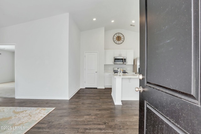 kitchen featuring dark wood-style flooring, stainless steel appliances, light countertops, white cabinets, and baseboards