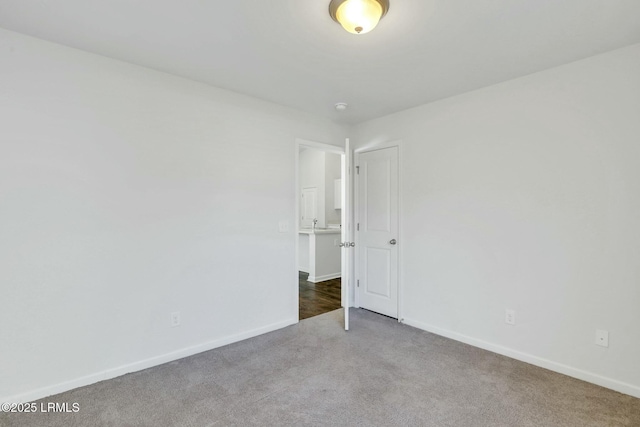 carpeted empty room featuring baseboards