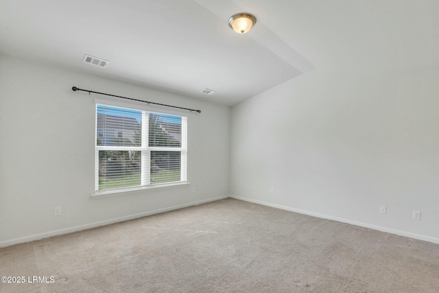 unfurnished room featuring light colored carpet, visible vents, lofted ceiling, and baseboards