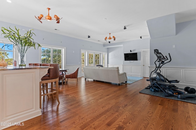 living room with hardwood / wood-style flooring, ornamental molding, and a notable chandelier