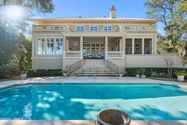 back of house featuring a fenced in pool, a sunroom, french doors, and a balcony