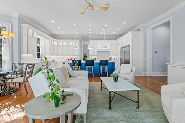 living room with hardwood / wood-style floors, crown molding, and ceiling fan