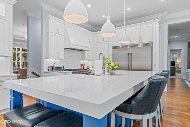 kitchen with stainless steel built in fridge, custom range hood, pendant lighting, a large island, and white cabinets