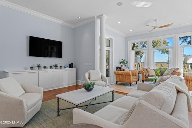 living room featuring decorative columns, ornamental molding, ceiling fan, and light hardwood / wood-style flooring