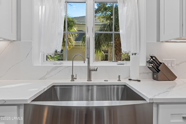 interior details with light stone countertops, sink, and white cabinets