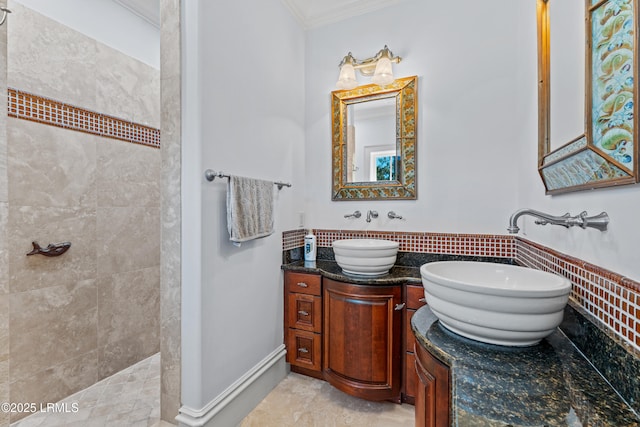 bathroom with a tile shower, vanity, and ornamental molding