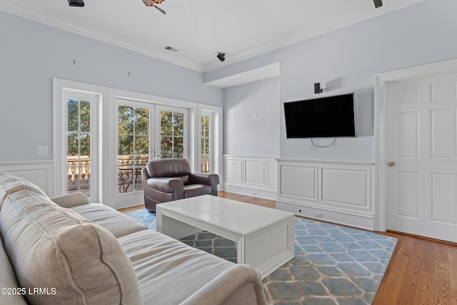 living room featuring crown molding, french doors, and light wood-type flooring