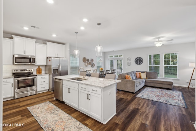 kitchen featuring appliances with stainless steel finishes, pendant lighting, sink, white cabinets, and dark hardwood / wood-style flooring