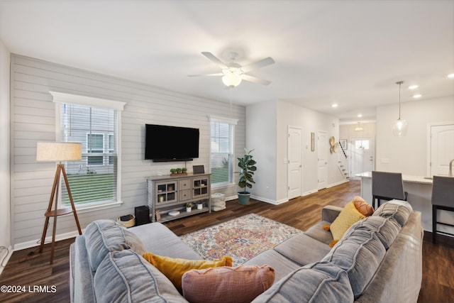 living room featuring dark hardwood / wood-style flooring, ceiling fan, and wood walls