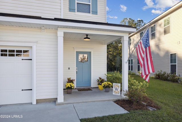 entrance to property with covered porch and a lawn