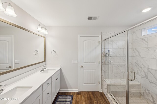 bathroom with wood-type flooring, a shower with shower door, and vanity