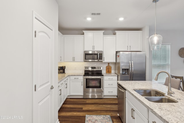 kitchen with decorative light fixtures, white cabinetry, sink, stainless steel appliances, and light stone countertops