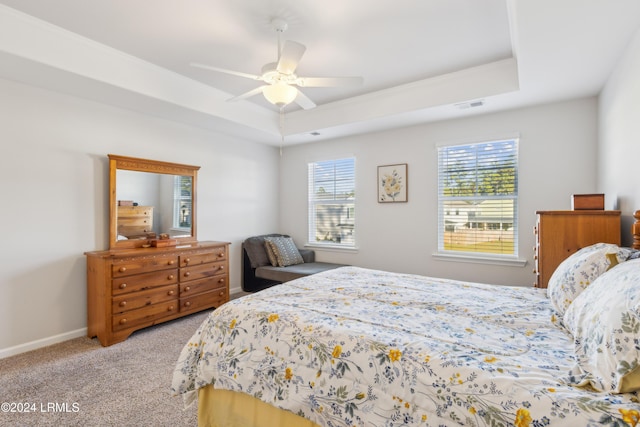 bedroom featuring ceiling fan, a tray ceiling, and light colored carpet