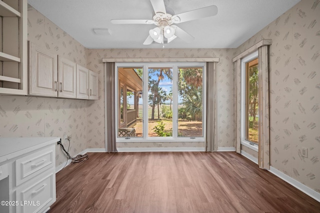 647 Island Cir E, Saint Helena Island, SC 29920 - unfurnished dining area with wood finished floors, ceiling fan, and wallpapered walls