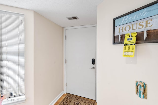 doorway with visible vents, a textured ceiling, and wood finished floors