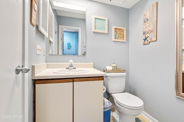 half bathroom with toilet, baseboards, and vanity