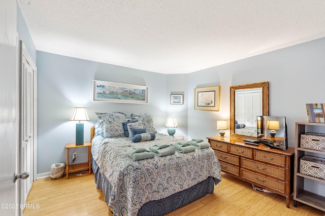 bedroom with light wood-style flooring, a closet, baseboards, and a textured ceiling