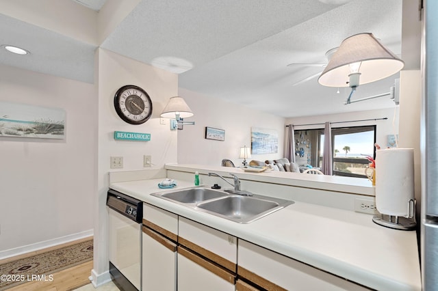 kitchen with light countertops, white cabinets, white dishwasher, a sink, and light wood-type flooring