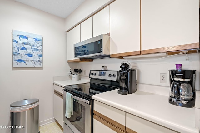 kitchen with light countertops, appliances with stainless steel finishes, light floors, and white cabinets