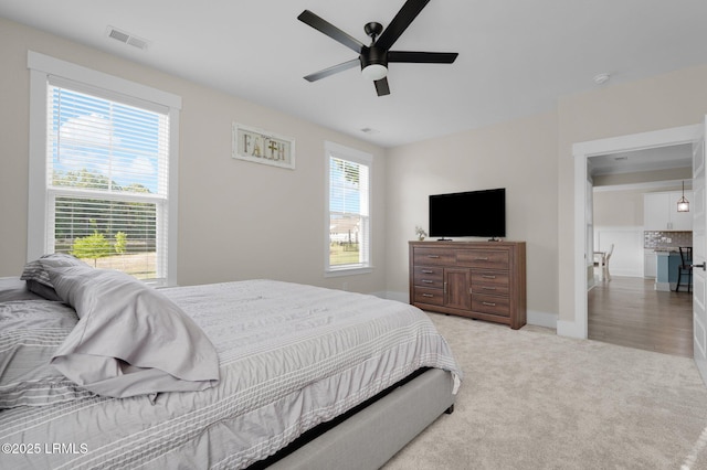 bedroom with baseboards, visible vents, ceiling fan, and light colored carpet