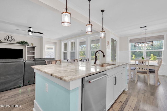 kitchen with an island with sink, stainless steel dishwasher, light wood-style floors, a sink, and crown molding