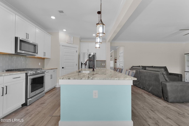 kitchen featuring crown molding, appliances with stainless steel finishes, and open floor plan