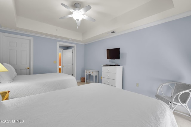 carpeted bedroom with a tray ceiling and ceiling fan