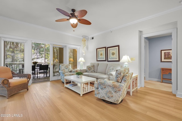 living room featuring ornamental molding, ceiling fan, and light wood-type flooring