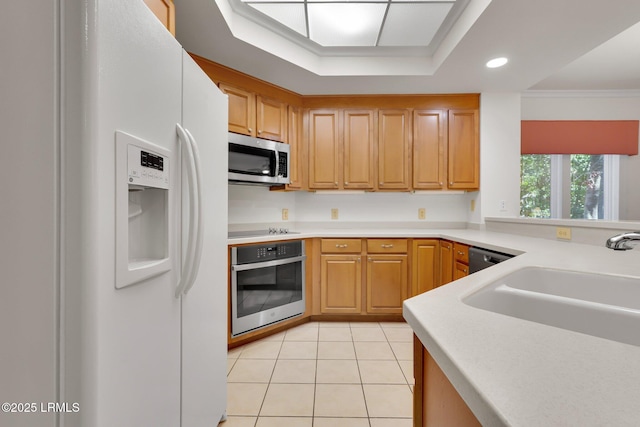 kitchen featuring sink, stainless steel appliances, ornamental molding, light tile patterned flooring, and a raised ceiling