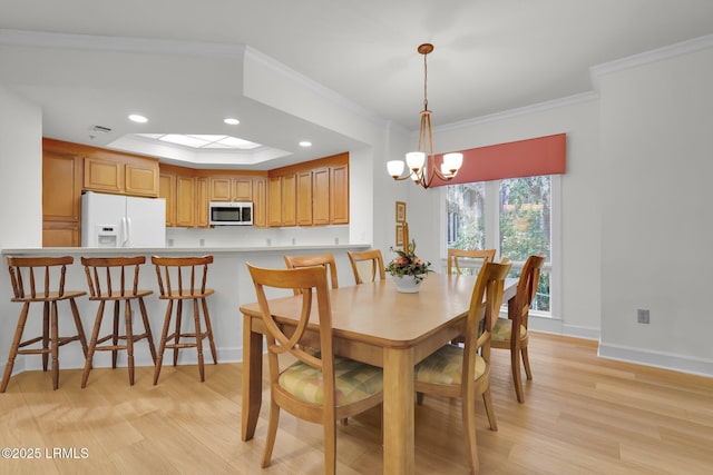 dining space with crown molding, a notable chandelier, a skylight, and light wood-type flooring