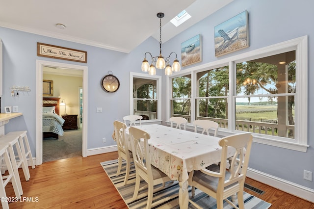 dining area with baseboards, crown molding, light wood finished floors, and an inviting chandelier