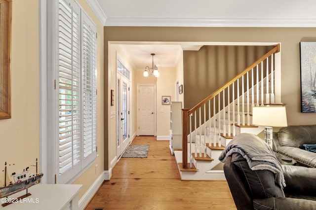 foyer with light wood-type flooring, an inviting chandelier, stairway, and ornamental molding