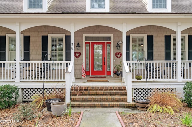 doorway to property with a porch and roof with shingles