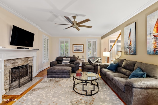 living room with ornamental molding, stairway, a fireplace, and light wood-style flooring