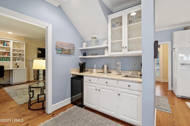 kitchen featuring wine cooler, a sink, light wood-style floors, ornamental molding, and white fridge with ice dispenser